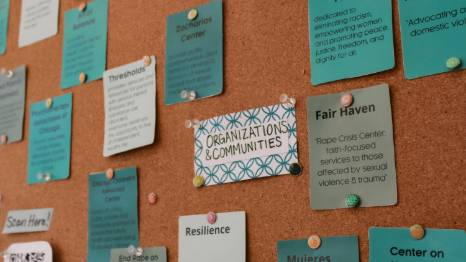 A corkboard displays various teal and green cards listing organizations, communities, and resources, including Fair Haven and Thresholds, pinned with pushpins.