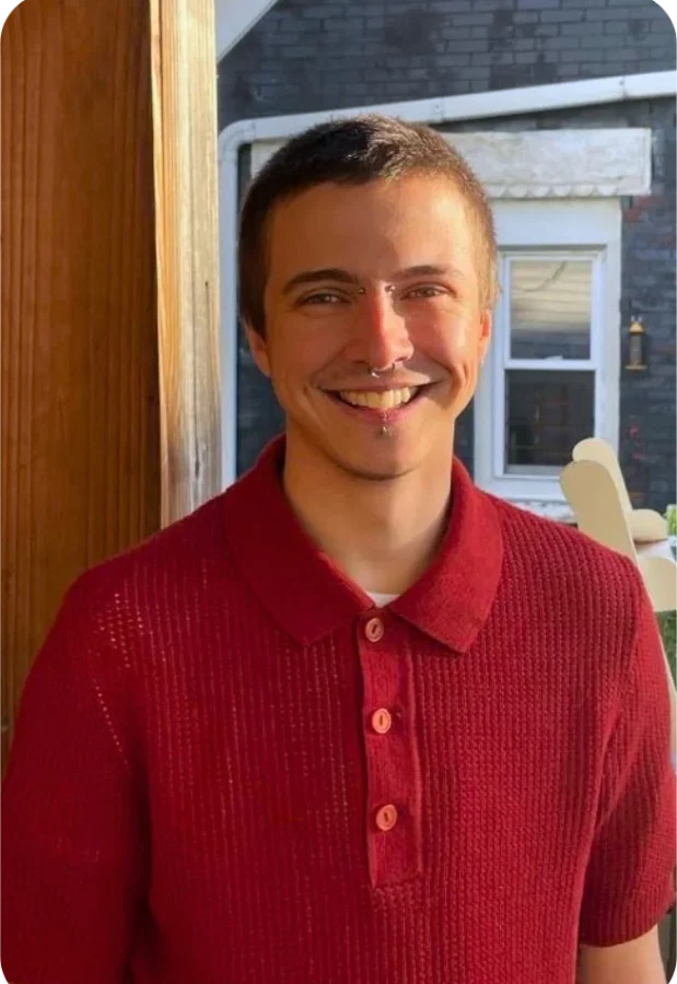 Wes Kendall is standing at a sunny window, smiling, and wearing a red polo shirt.